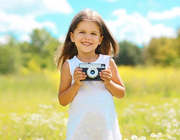 Feliz niño sonriente con cámara retro vintage divertirse al aire libre —  Fotos de Stock