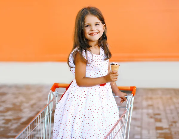 Menina sorridente feliz no carrinho de compras com sorvete saboroso — Fotografia de Stock