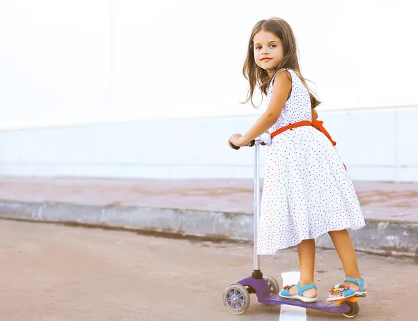 Divertida menina no vestido na scooter na cidade — Fotografia de Stock