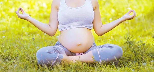 Mulher grávida ioga ao ar livre no dia de verão na grama — Fotografia de Stock