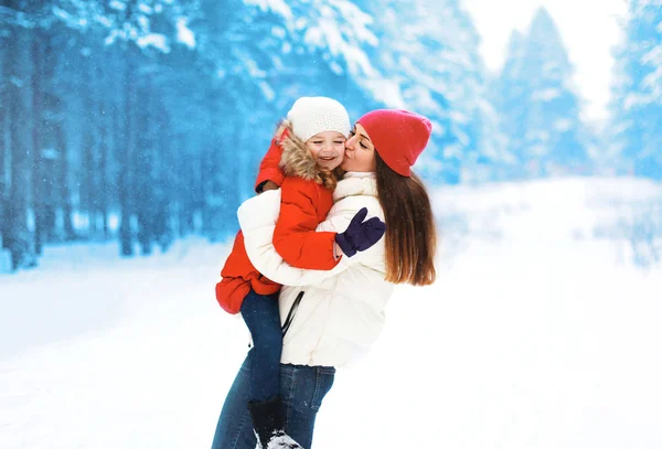 Gelukkig kind met moeder buitenshuis in besneeuwde winterdag — Stockfoto