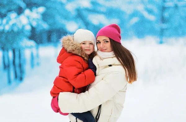 Gelukkig moeder en kind samen in besneeuwde dag tegen de snowfla — Stockfoto