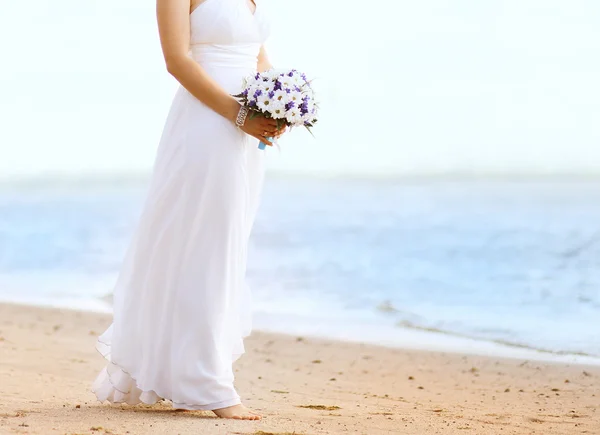 Beautiful bride with wedding bouquet outdoors on the coast sea — Stock Photo, Image