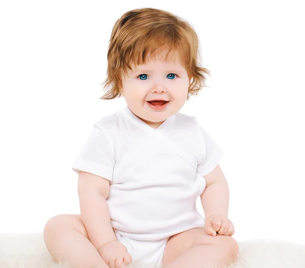 Обаятельный улыбающийся ребенок, сидящий на белом фоне — стоковое фото