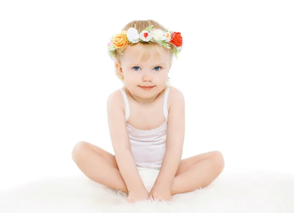 Kleines Mädchen mit Blumenkranz auf dem Kopf auf weißem Hintergrund — Stockfoto