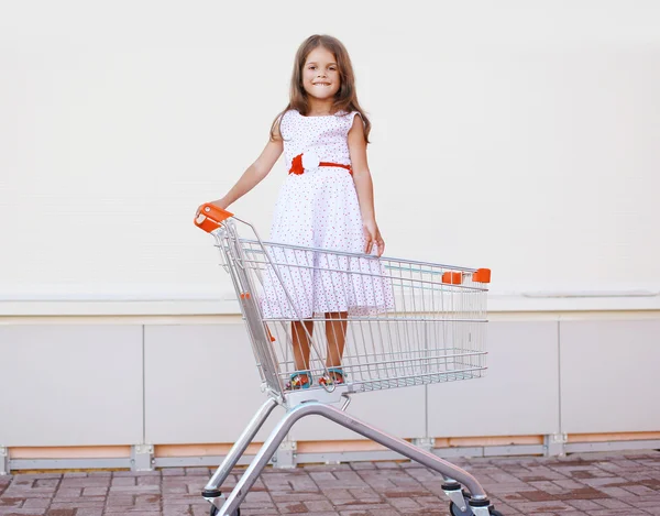 Beautiful little girl in shopping cart having fun outdoors again — Stock Photo, Image