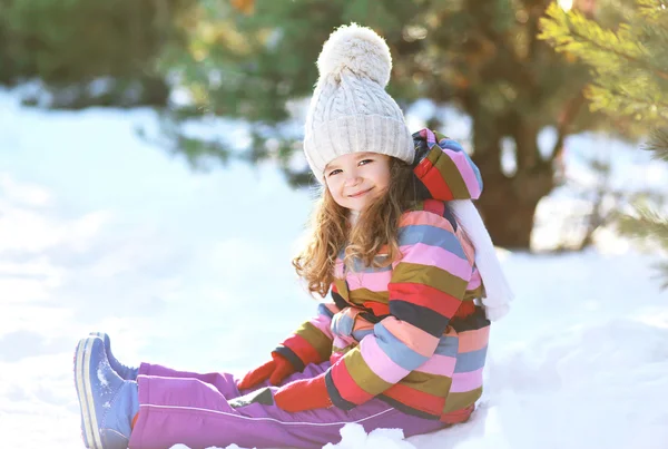 Маленький ребенок, сидящий на снегу, веселится в зимний день — стоковое фото