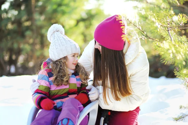 Moeder en kind in de slee plezier, zonnige winterdag — Stockfoto