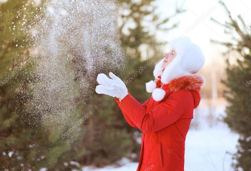 Happy woman having fun throws up snow in winter day