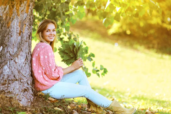 Jolie jolie femme élégante avec des feuilles d'érable à l'extérieur au soleil chaud — Photo