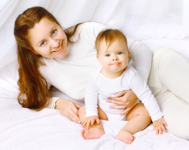 Güzel mutlu anne ve bebek evde yatakta eğleniyor