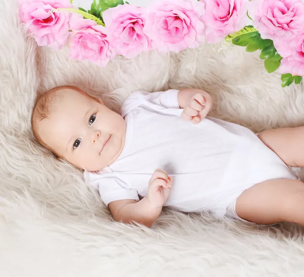 Söta baby och blommor på sängen, ovanifrån — Stockfoto