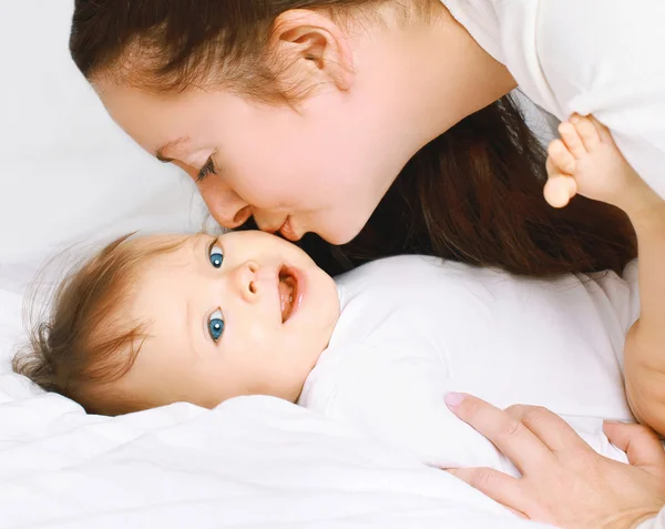 Мама целует малыша на кровати дома — стоковое фото