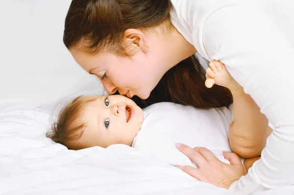 Madre besando lindo bebé en la cama en casa — Foto de Stock