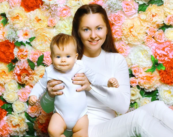 Szczęśliwa matka i dziecko przeciwko kolorowe kwiaty — Zdjęcie stockowe