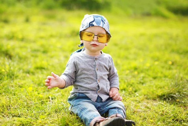 Positiva roliga lilla barnet i solglasögon på sommaren gräs — Stockfoto