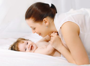 Mutlu anne ve bebek evde yatakta eğleniyor