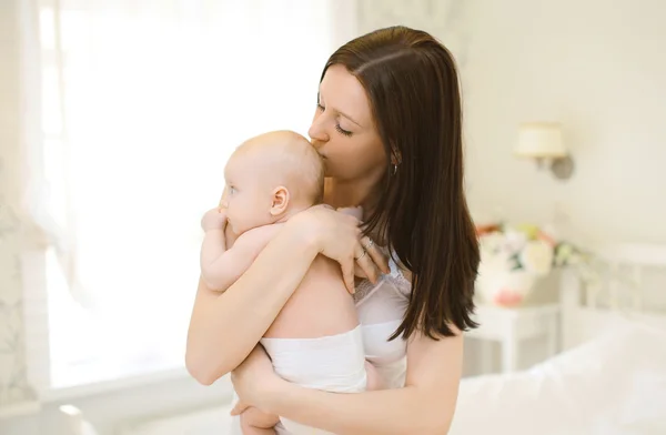 Glad mamma försiktigt kramar och kyssar baby på hem — Stockfoto