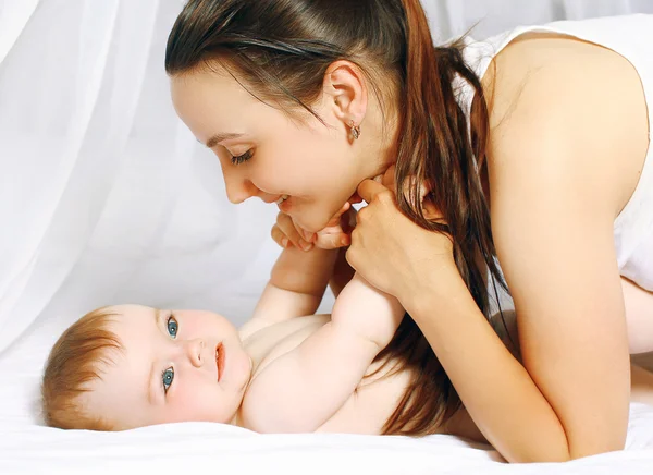 Happy mother and baby lying on bed at home Royalty Free Stock Photos