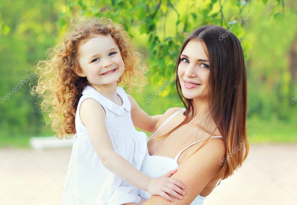 Portrait lovely young mother and cute daughter in sunny summer d