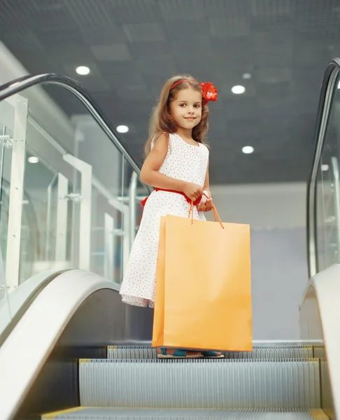Linda niña con bolsas de compras en el centro comercial —  Fotos de Stock