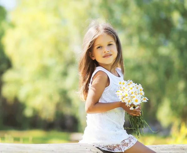 Sunny holčička s kyticí chamomiles na jaře — Stock fotografie