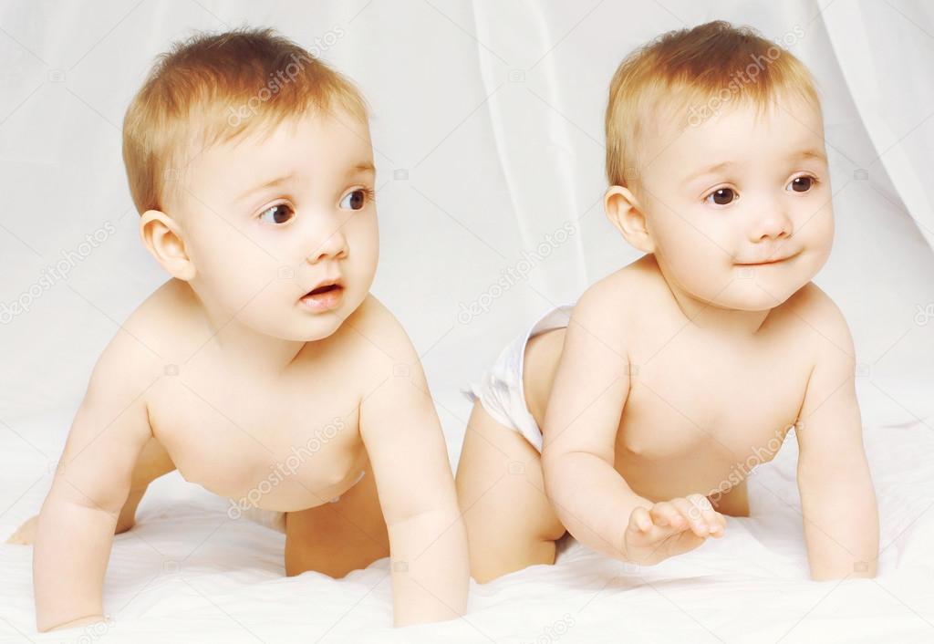 Two charming twins babies crawling on the bed