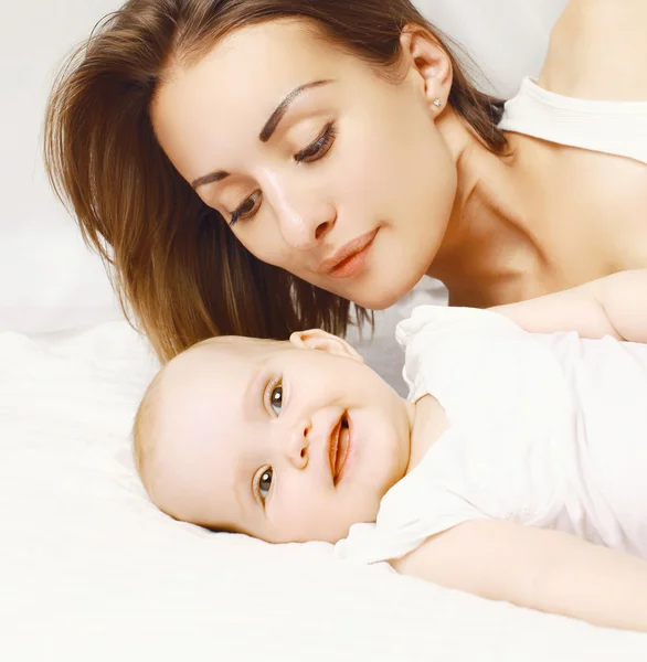 Retrato de primer plano del bebé alegre y la madre en la cama —  Fotos de Stock