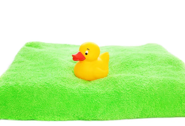 Brinquedo de pato de borracha amarela e toalha verde isolada em um backg branco — Fotografia de Stock