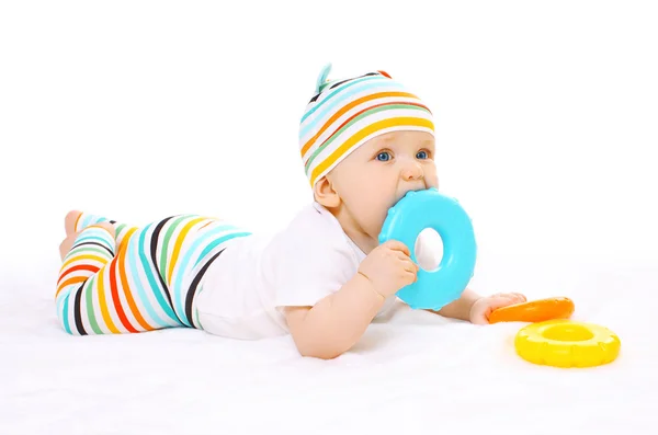 Colorful baby is lying on the floor and bites toy — Stock Photo, Image