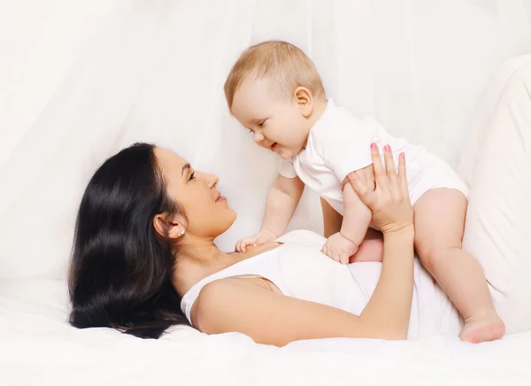 Mamma leker med hennes barn och ha roligt hemma på sängen — Stockfoto