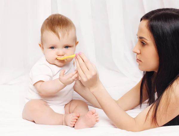 Mother feeds with a spoon baby at home — Stock Photo, Image