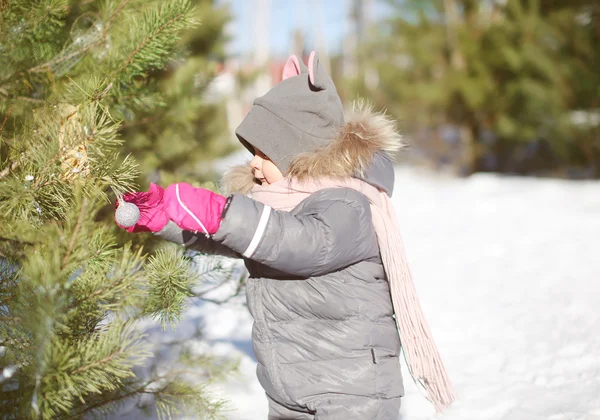 ? hild dekorerar en? hristmas träd bollar utomhus i solig vinterdag — Stockfoto