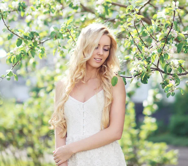 Pretty woman with curly hair in flowering garden — Stock Photo, Image