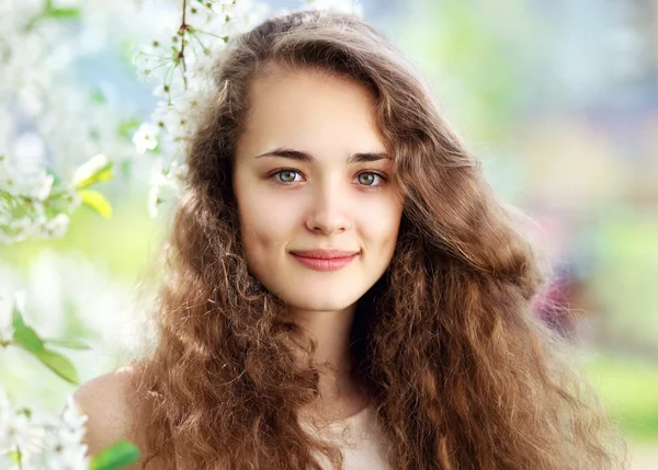Spring portrait of a beautiful young girl with curly hair in a f — Stock Photo, Image
