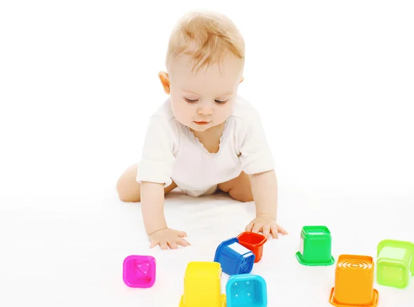 Младенец играет с разноцветными игрушками на полу — стоковое фото