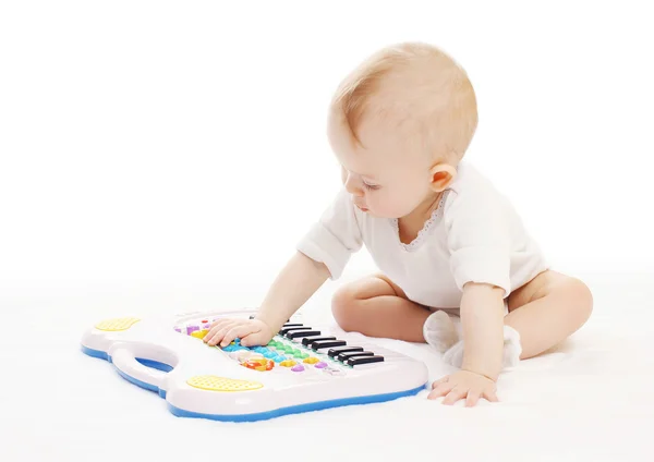Oyuncak piyano beyaz bir arka plan üzerinde oynamaya meraklı bebek — Stok fotoğraf