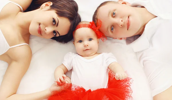 Beautiful young family lying together on the bed at home, parent — Stock Photo, Image