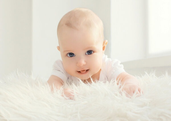 Closeup portrait of infant lying at home in white room near wind