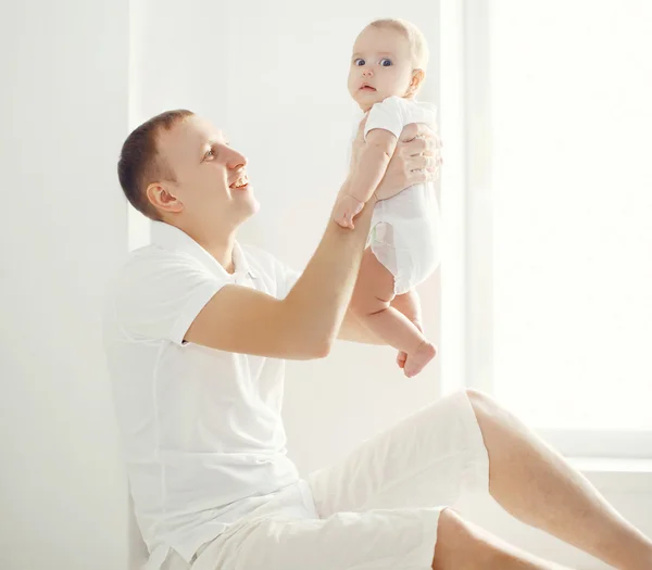 Glücklicher Vater hält sein Baby zu Hause im weißen Zimmer nea an den Händen — Stockfoto