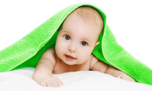Porträt eines süßen Babys, das unter einem grünen Handtuch auf einem weißen Rücken liegt — Stockfoto
