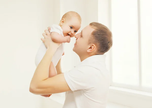 Portrait of happy father holding on hands his baby at home — Stock Photo, Image