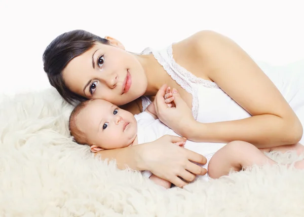 Portrait of happy young mother and baby lying on the bed at home — Stock Photo, Image