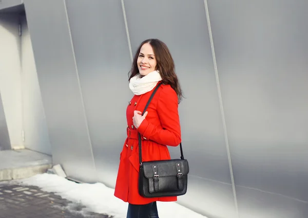 Feliz hermosa mujer joven vestida con una chaqueta roja con bolsa negra — Foto de Stock