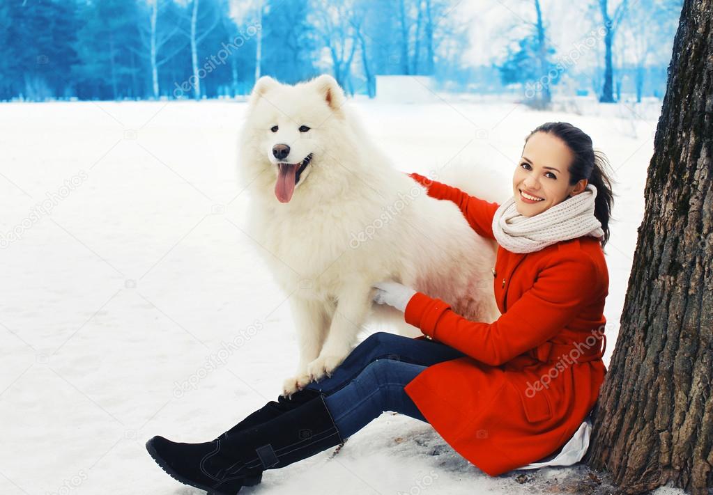 Happy woman owner having fun with white Samoyed dog outdoors on 