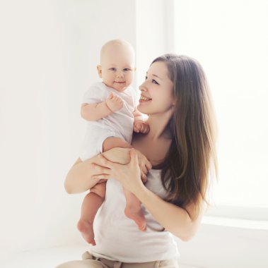 Portre aile evde, mutlu genç anne ve bebek ışık ro