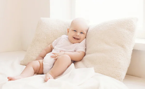 Confort, pequeño bebé feliz acostado en las almohadas en casa en la luz — Foto de Stock