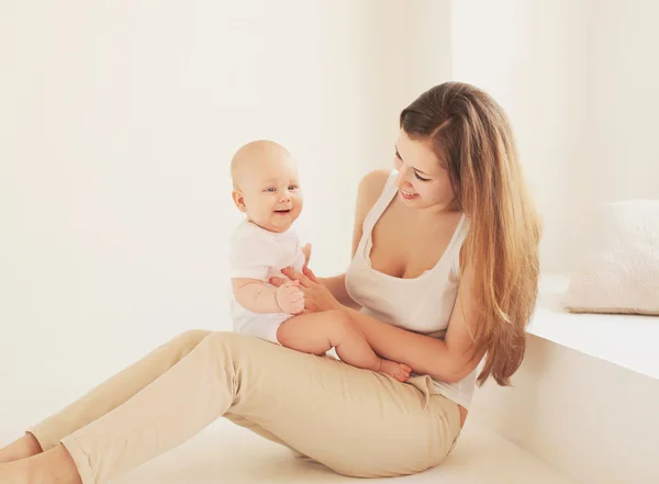 Happy young mother and baby together at home in white room near — Stock Photo, Image