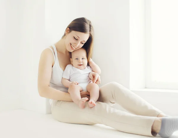 Happy young mother with baby at home in white room near window — Stock Photo, Image