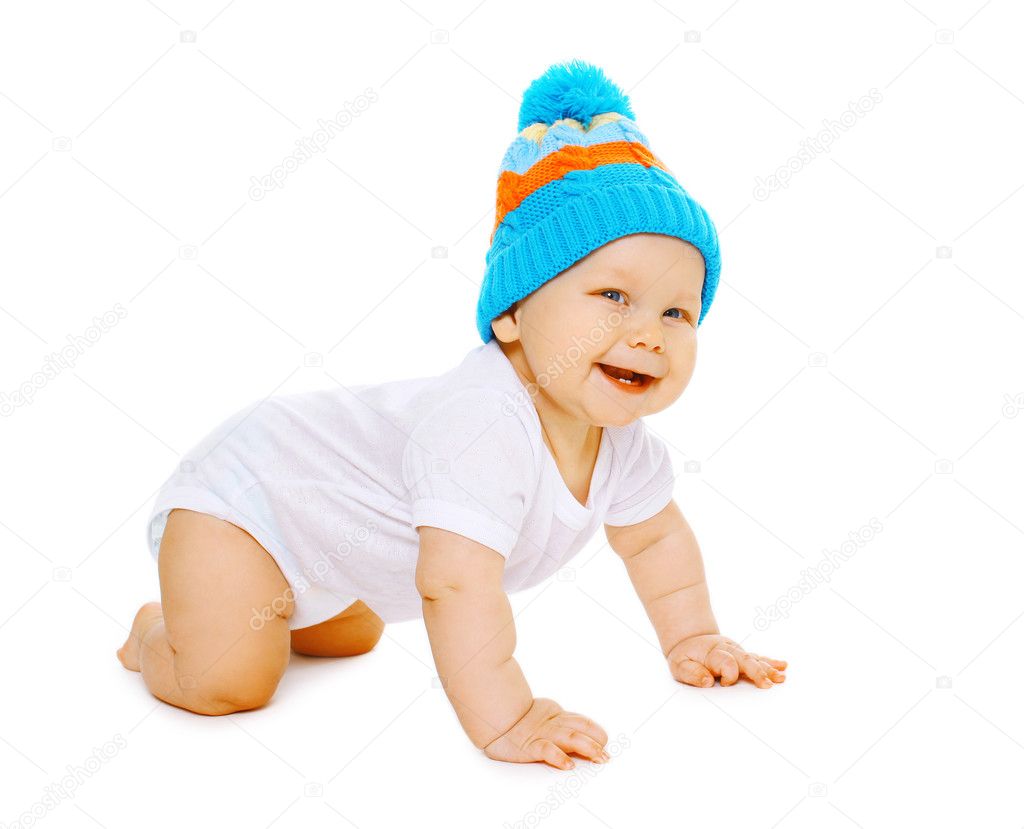 Laughing positive little baby crawls in the knitted hat 